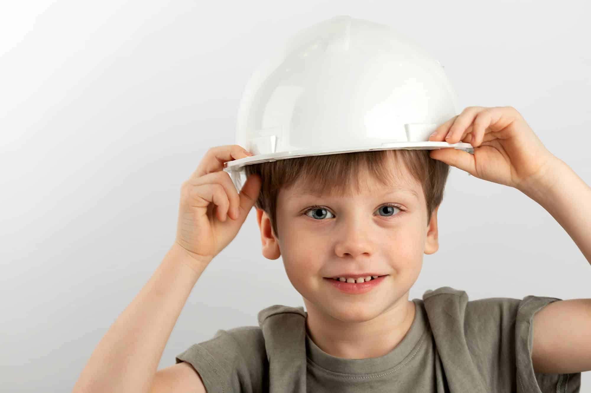 A boy in a work helmet on a light background